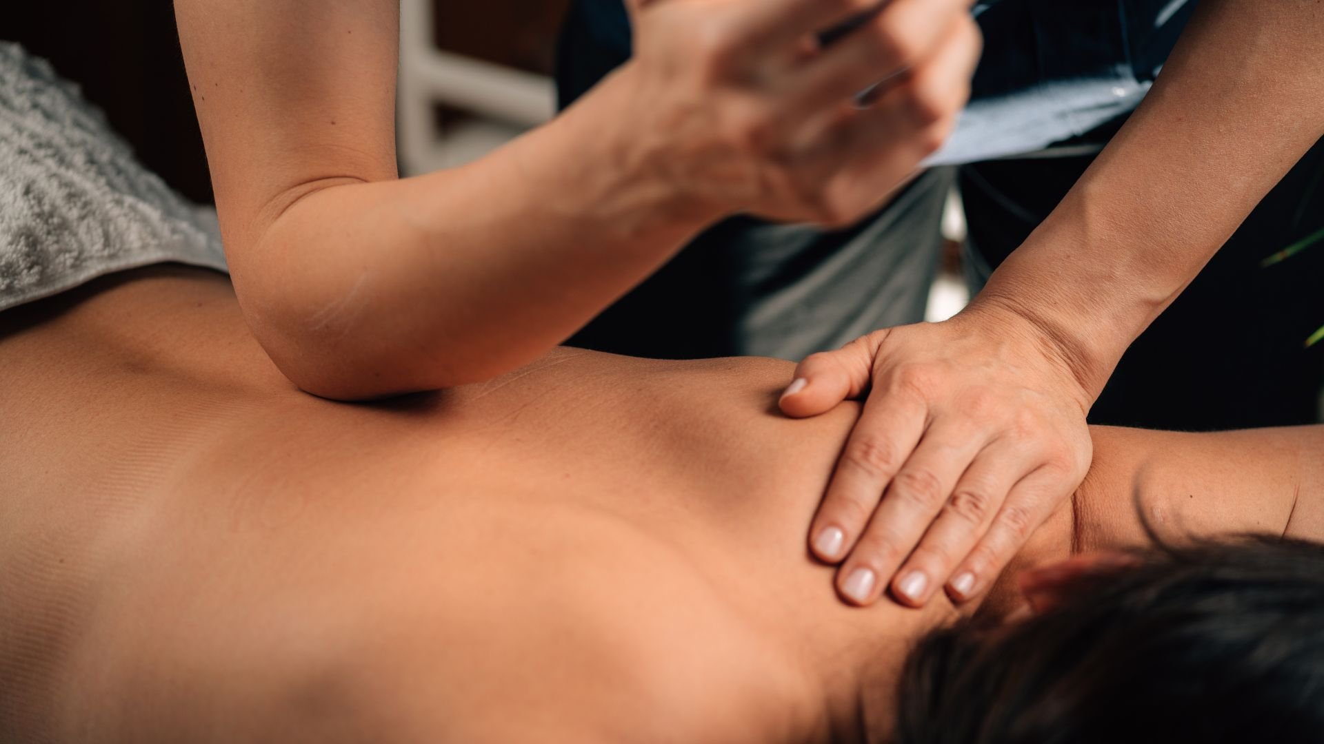 Massage therapist performing deep tissue back massage in professional setting
