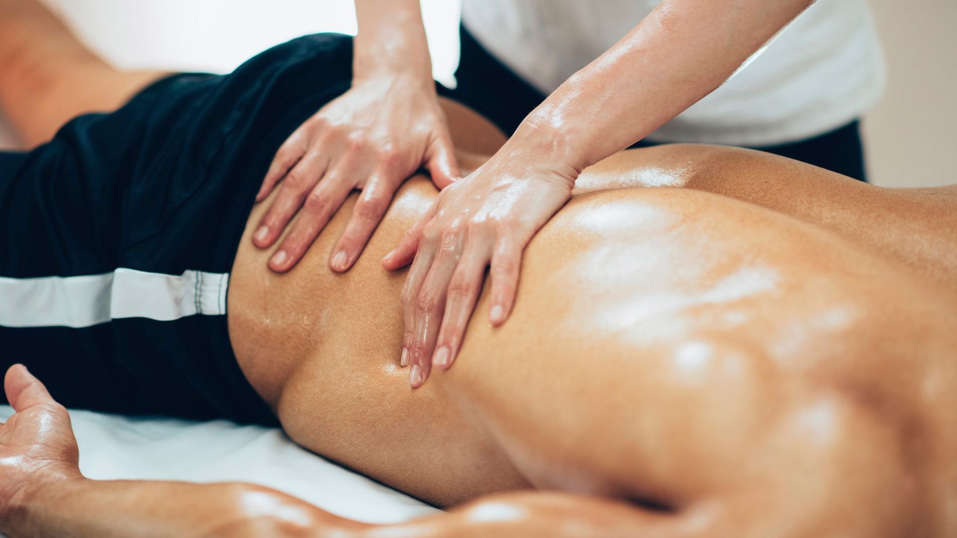 Hands performing massage on oiled back during professional spa treatment